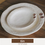 Assiette blanche élégante avec de petits boutons décoratifs sur les bords, posée sur une surface en bois.