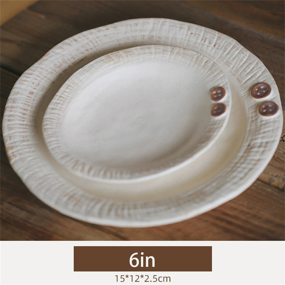 Assiette blanche élégante avec de petits boutons décoratifs sur les bords, posée sur une surface en bois.