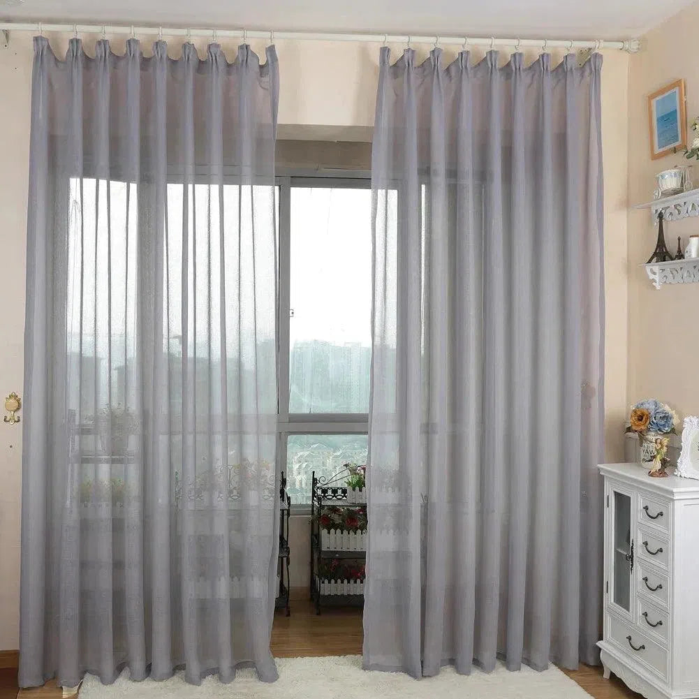 Rideaux élégants de couleur gris clair dans un salon contemporain, apportant une touche de sophistication et de modernité à la décoration intérieure. L'installation permet une diffusion idéale de la lumière naturelle tout en assurant une certaine intimité. Accessoires adjacents en harmonie avec le style lumineux et épuré.