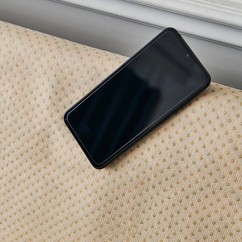 Téléphone portable noir posé sur un tapis beige texturé, représentant un équipement technologique moderne sur un ameublement douillet.