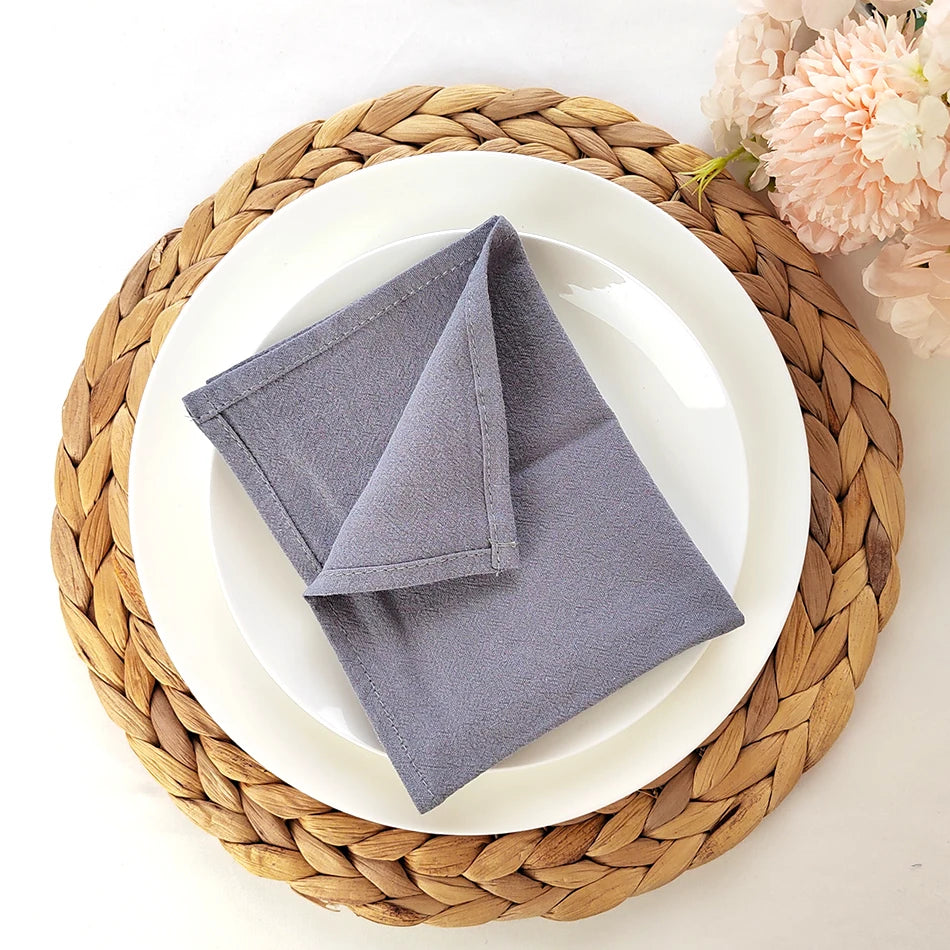 Un ensemble de table élégant avec une nappe grise et une jolie fleur rose sur un tapis de table tressé.