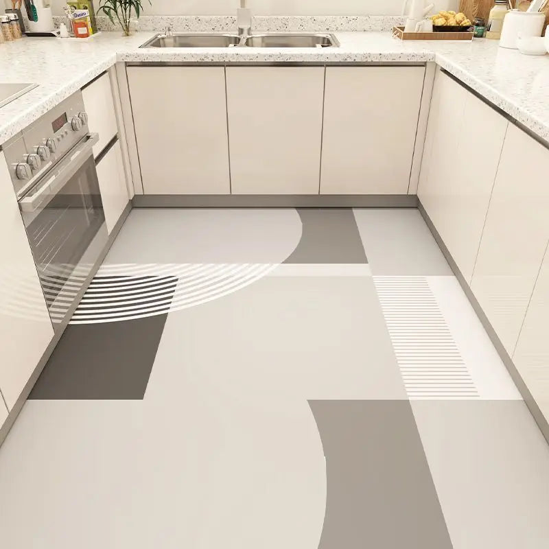 Cuisine moderne et élégante avec des comptoirs en granite blanc, des armoires beiges et un sol en carrelage aux motifs géométriques monochromes.