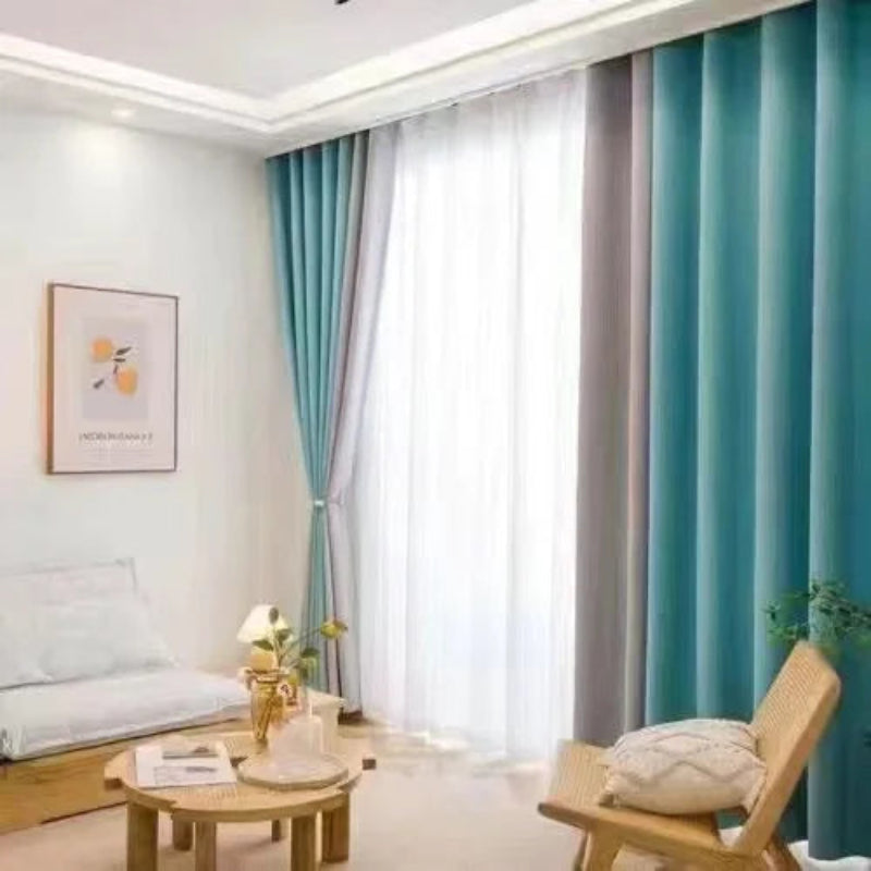 Rideaux occultants bleu vert et gris dans un intérieur lumineux, installés sur rail au plafond, accompagnés d'un canapé blanc et de mobilier en bois clair.