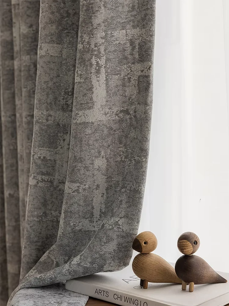 Rideau occultant gris moderne avec motif géométrique subtil, idéal pour ajouter une touche élégante à votre salon ou chambre. Accessoires décoratifs boisés à côté pour une ambiance chaleureuse.