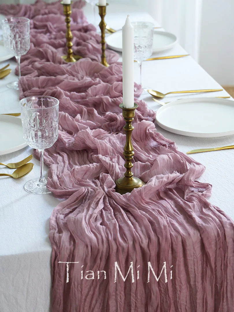 Cette image montre un élégant couvert de table avec des accents de rose, des bougies dorées et des assiettes blanches, créant une ambiance chaleureuse et raffinée.