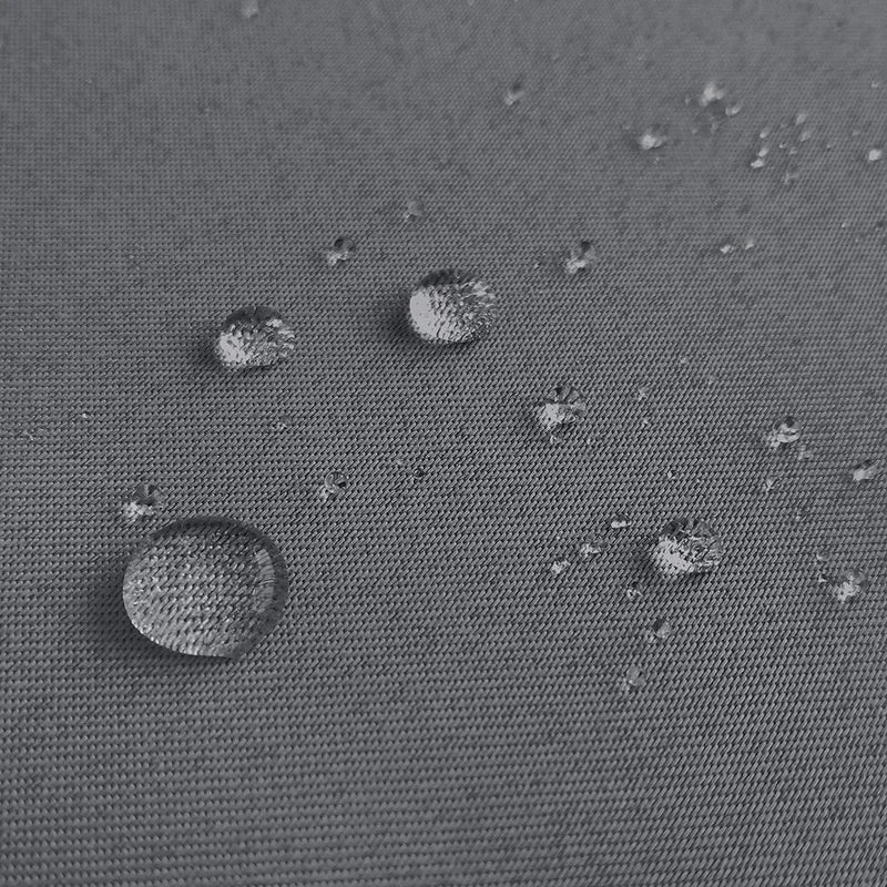 Gouttes d'eau sur une surface grise imperméable, illustrant la résistance à l'humidité et la protection efficace contre les intempéries, idéal pour les vêtements et équipements extérieurs.