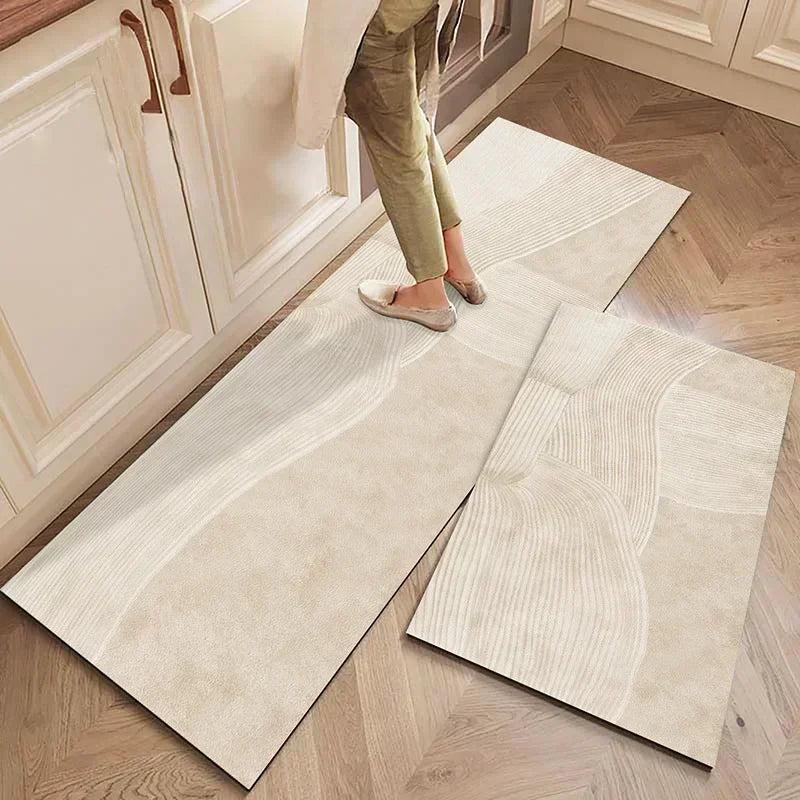 Des carreaux de carrelage beige avec un motif ondulé sur un sol en bois, avec des pieds de la personne photographiée au premier plan.
