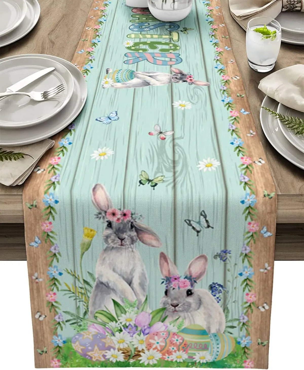 Chemin de table décoré de deux lapins mignons, d'œufs de Pâques et de fleurs printanières, sur fond de planches de bois.