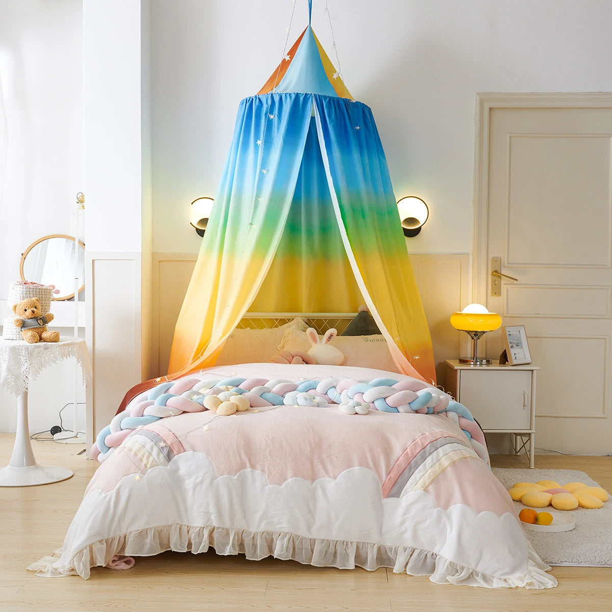 Une magnifique chambre d'enfant aux couleurs arc-en-ciel, avec un lit douillet entouré d'un baldaquin aux teintes dégradées et de délicats accessoires qui créent une atmosphère de rêve.