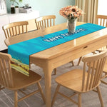 La table à manger de style moderne avec des fleurs dans un vase et un joli chemin de table bleu et vert crée une ambiance chaleureuse et accueillante dans cette pièce.