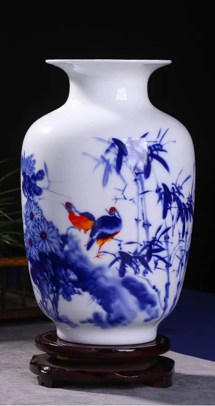Un magnifique vase en porcelaine blanche et bleue orné de motifs floraux et d'oiseaux de couleur vive.