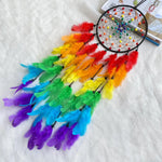 Un magnifique capteur de rêves coloré avec des plumes multicolores disposées radialement autour d'un cadre circulaire décoré de perles.