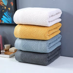 Une pile de serviettes de bain moelleuses de différentes couleurs et motifs, offrant une variété de choix pour une salle de bain accueillante.