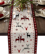 Une table de Noël joliment décorée avec une nappe présentant des motifs de cerfs et de flocons de neige dans des tons rouges et noirs.