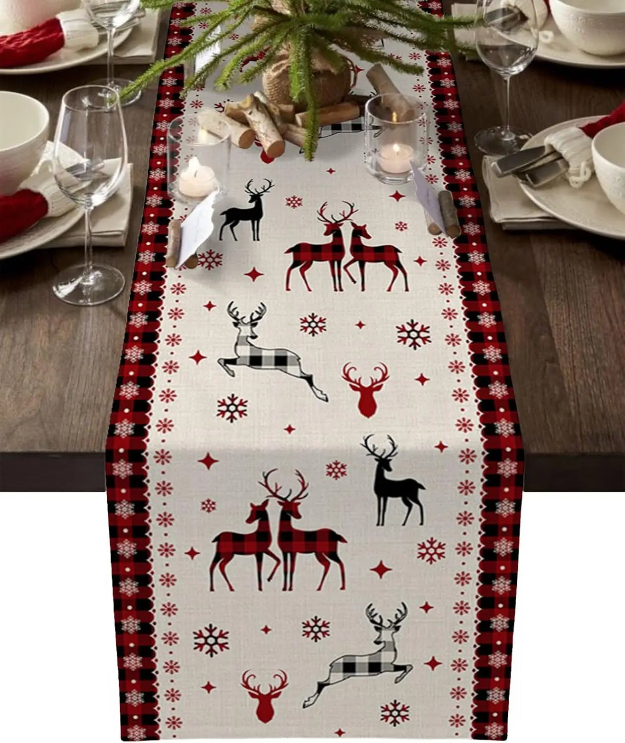 Une table de Noël joliment décorée avec une nappe présentant des motifs de cerfs et de flocons de neige dans des tons rouges et noirs.
