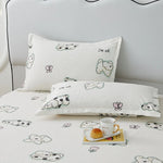 Ensemble de literie douillet avec des motifs de nuages mignons imprimés sur un fond blanc cassé, créant une ambiance relaxante et agréable dans la chambre.