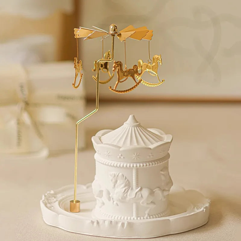 Une décoration de table élégante et ludique avec un carrousel doré miniature au-dessus d'un cadre blanc orné de motifs enfantins.