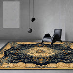 Tapis oriental orné de motifs floraux et d'éléments décoratifs dorés, posé sur un sol gris dans un intérieur minimaliste avec des chaises noires.