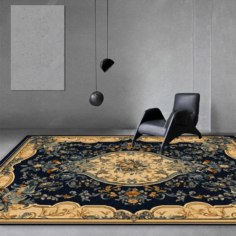 Tapis oriental orné de motifs floraux et d'éléments décoratifs dorés, posé sur un sol gris dans un intérieur minimaliste avec des chaises noires.