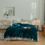 Une chambre confortable avec un lit douillet recouvert d'un plaid en velours bleu profond, une table de chevet en bois, un cadre avec une illustration artistique et une plante d'intérieur qui apportent une touche décorative.