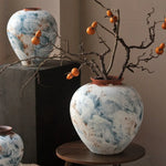 vase artisanal bleu blanc marron marbré rustique arrangement floral branches fruits decoration intérieure