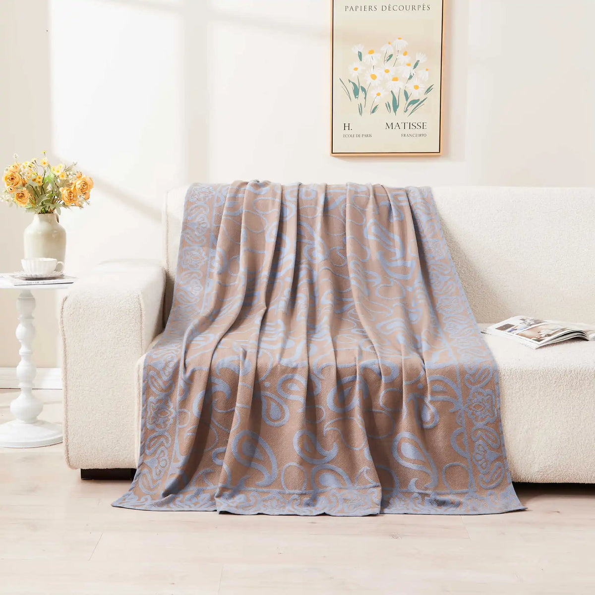 Une couverture moelleuse ornée d'un motif abstrait apaisant, accentuée par des fleurs dans un vase, créant une atmosphère chaleureuse et accueillante.