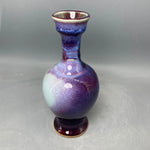 Un vase en céramique aux teintes violettes et bleues avec des motifs et des touches de couleurs irisées.