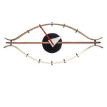 horloge murale forme œil moderne or marron foncé aiguilles rouge blanche minimaliste