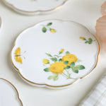 Des fleurs jaunes et des papillons sur un plat décoratif en porcelaine fine.