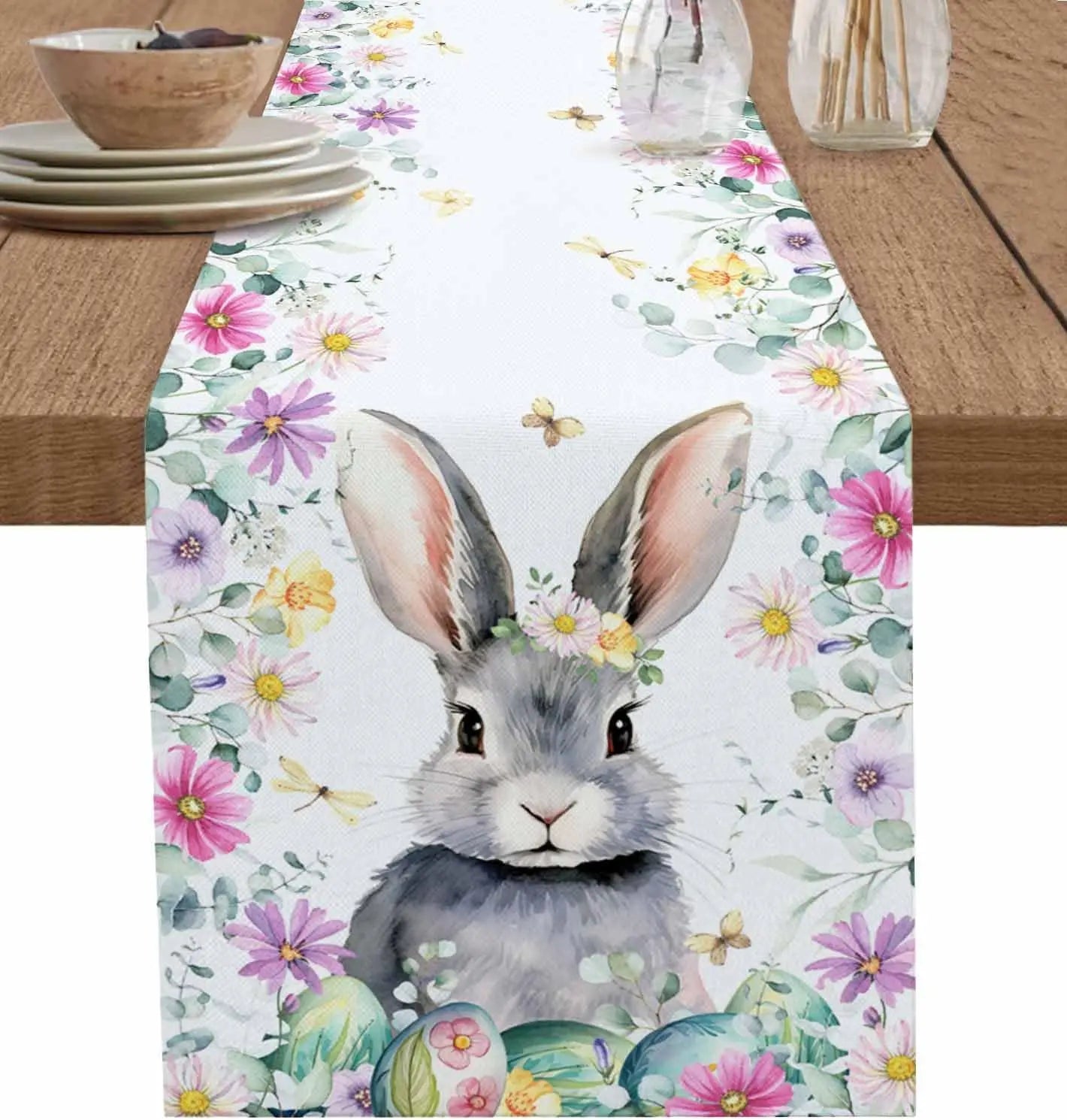 Un lapin gris mignon parmi des fleurs colorées et des papillons, créant une scène printanière charmante sur ce chemin de table fleuri.