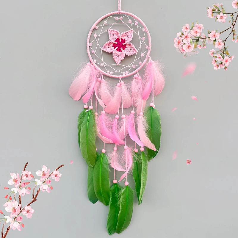 Un magnifique attrape-rêves rose et vert avec des plumes flottantes et une fleur épanouie, entouré par des fleurs de cerisier printanières en arrière-plan.