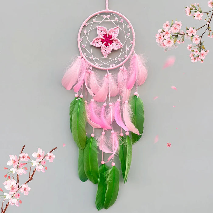 Un magnifique attrape-rêves rose et vert avec des plumes flottantes et une fleur épanouie, entouré par des fleurs de cerisier printanières en arrière-plan.