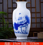 Ce vase en porcelaine blanche présente une belle décoration peinte en bleu représentant une scène naturelle avec des fleurs et des plantes.