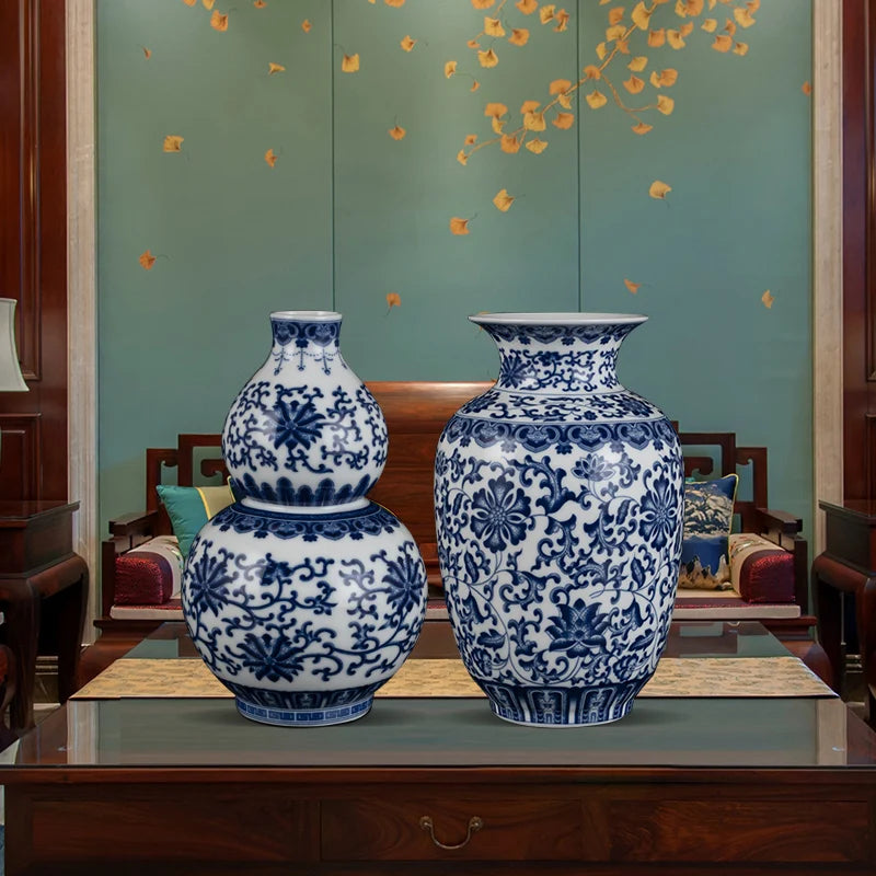 Deux vases en porcelaine bleue et blanche décorés de motifs floraux élégants, placés sur un meuble en bois sombre dans un cadre décoratif avec un mur de fond vert.