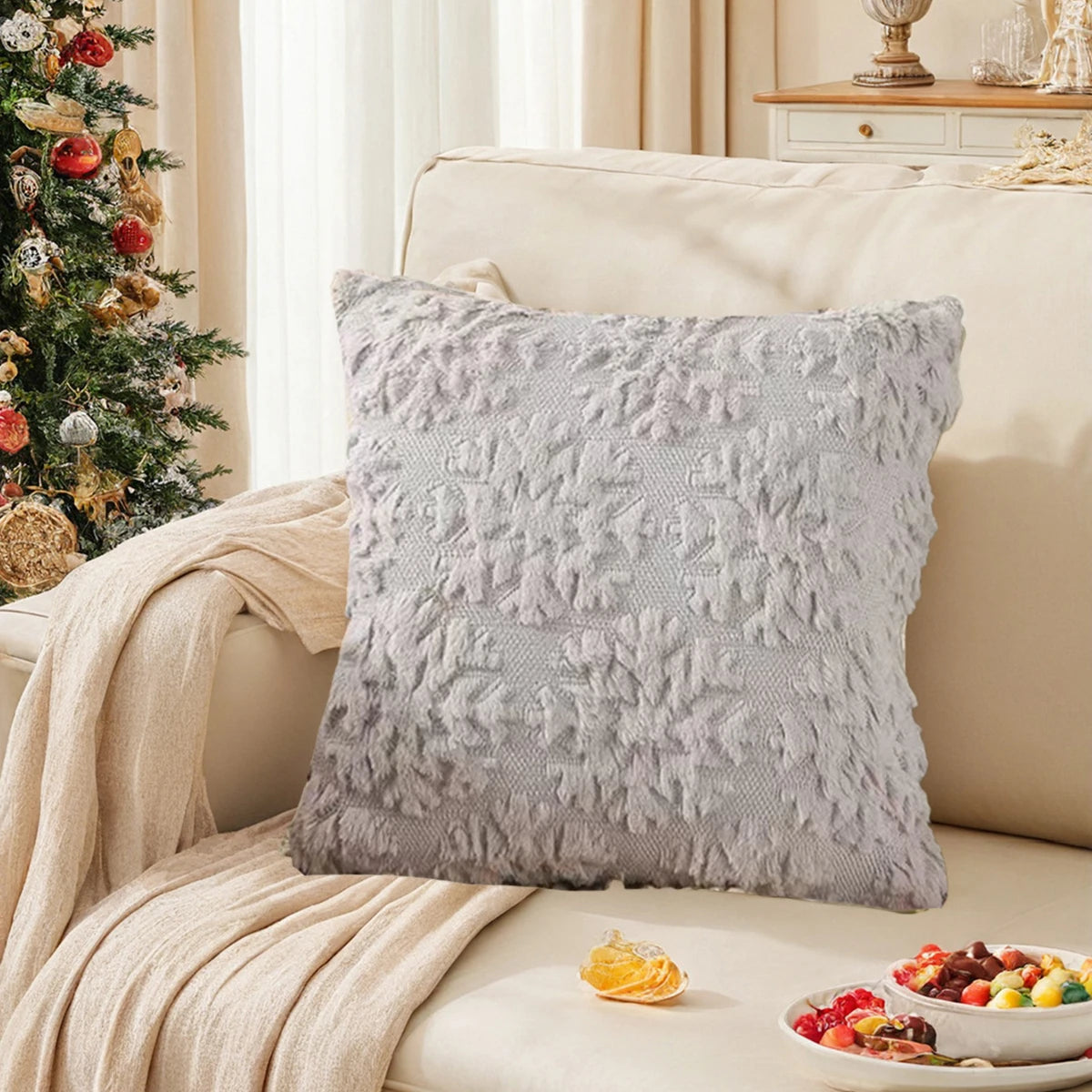 Un oreiller décoratif douillet gris clair orné de motifs texturés et posé sur un lit confortable dans un cadre cosy et féérique, complété de fruits colorés.