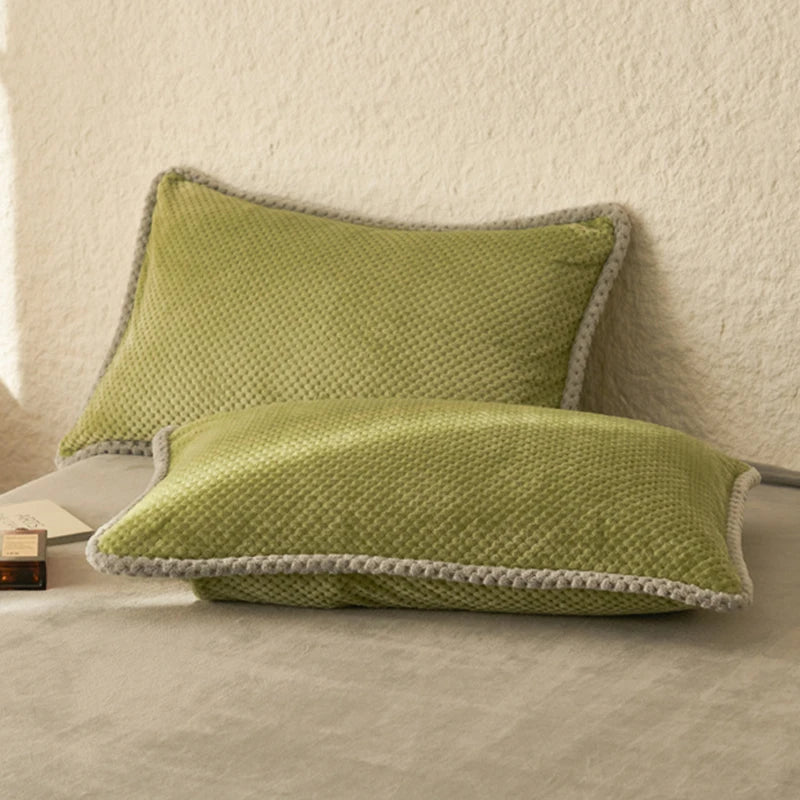 Deux oreillers verts foncés avec bordure grise sur fond blanc créant une ambiance douce et apaisante.