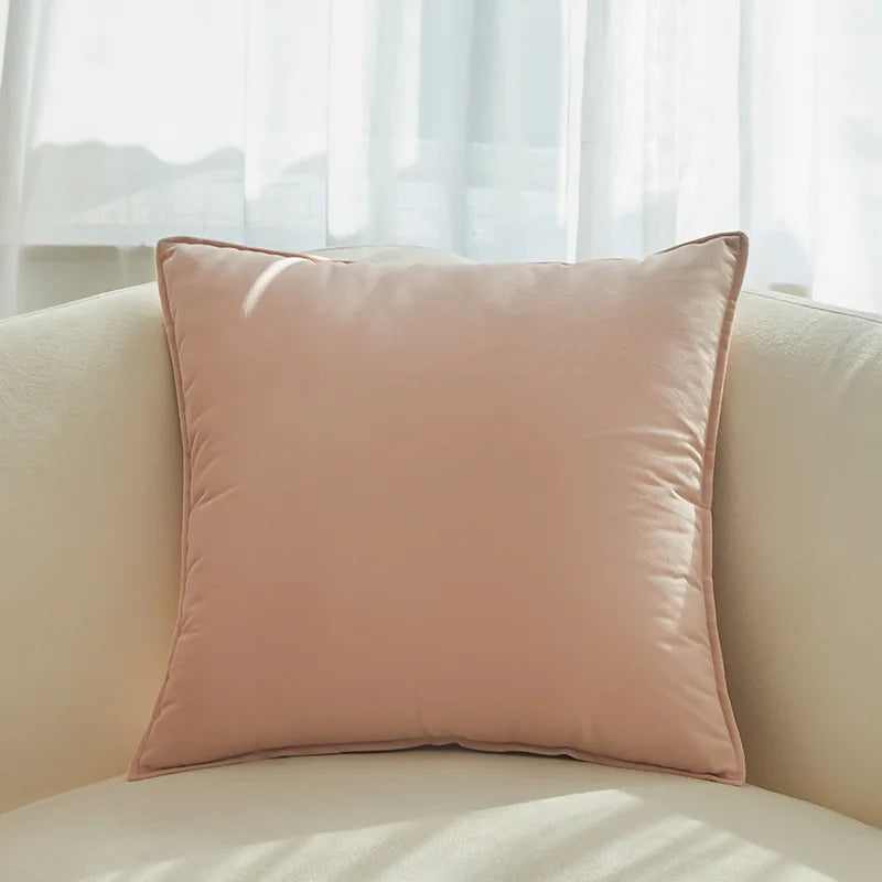 Un coussin rose pastel confortable posé sur un canapé beige dans un intérieur lumineux.