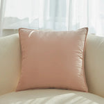 Un coussin rose pastel confortable posé sur un canapé beige dans un intérieur lumineux.