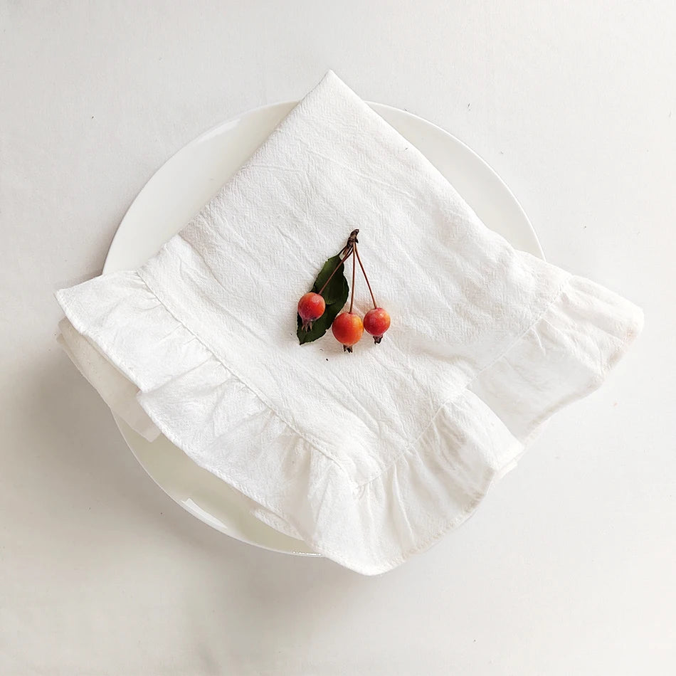 Une grappe de petites baies rouges posée délicatement sur un linge blanc plié, offrant une composition minimaliste et élégante.