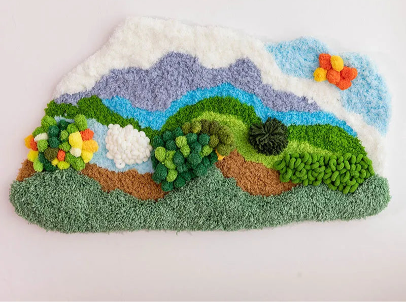 Tapis textile appliqué représentant un paysage de montagne avec des fleurs colorées.