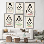 Des affiches décoratives de tests oculaires modernes ornent le mur au-dessus d'un salon confortable avec des meubles en bois et en textile.
