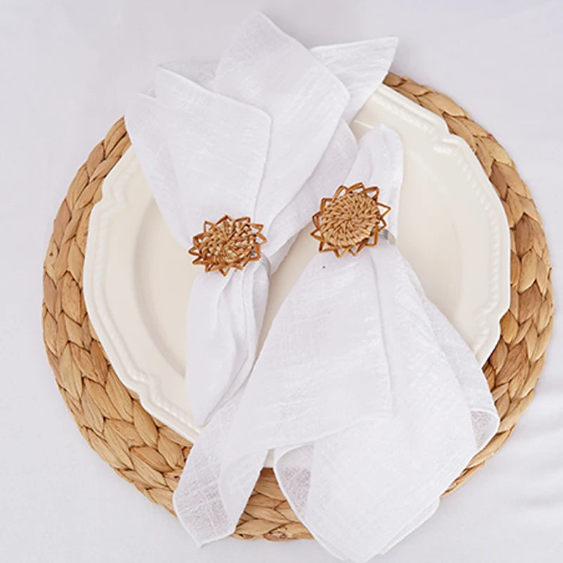 Serviettes blanches sur un plateau en osier avec décorations florales en métal doré.