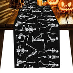 Une nappe de table décorée d'un motif squelettique en noir et blanc, entourée de citrouilles sculptées et de bougies allumées, créant une ambiance mystérieuse et effrayante parfaite pour une soirée d'Halloween.