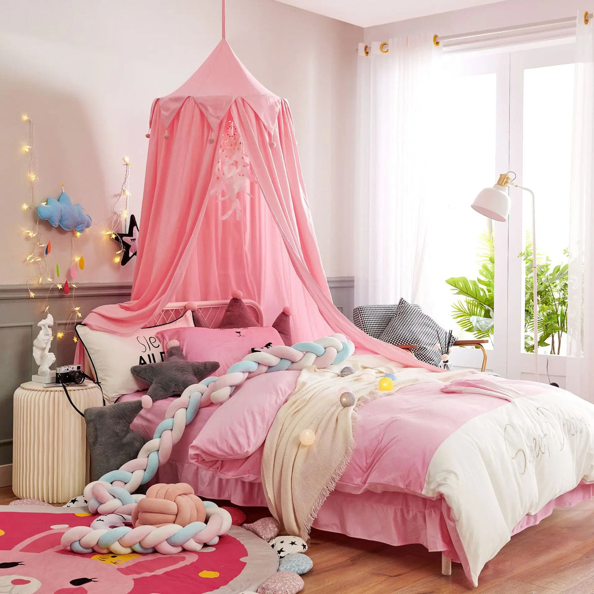 La chambre d'enfant est élégamment décorée avec des éléments roses, blancs et gris, créant une ambiance chaleureuse et accueillante pour un jeune occupant.