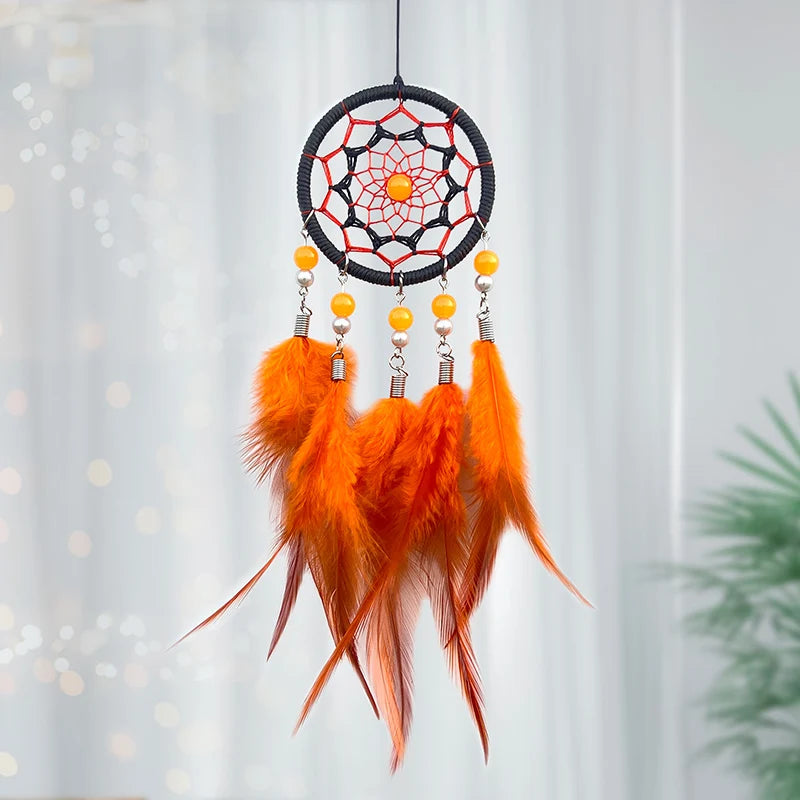 Un rêve attrapeur orange et noir décoré de plumes et de perles suspendues à un cadre circulaire en fil tressé.