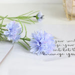 décoration intérieure bouquet fleurs artificielles bleues blanches roses longues tiges vertes vase transparent festonnée