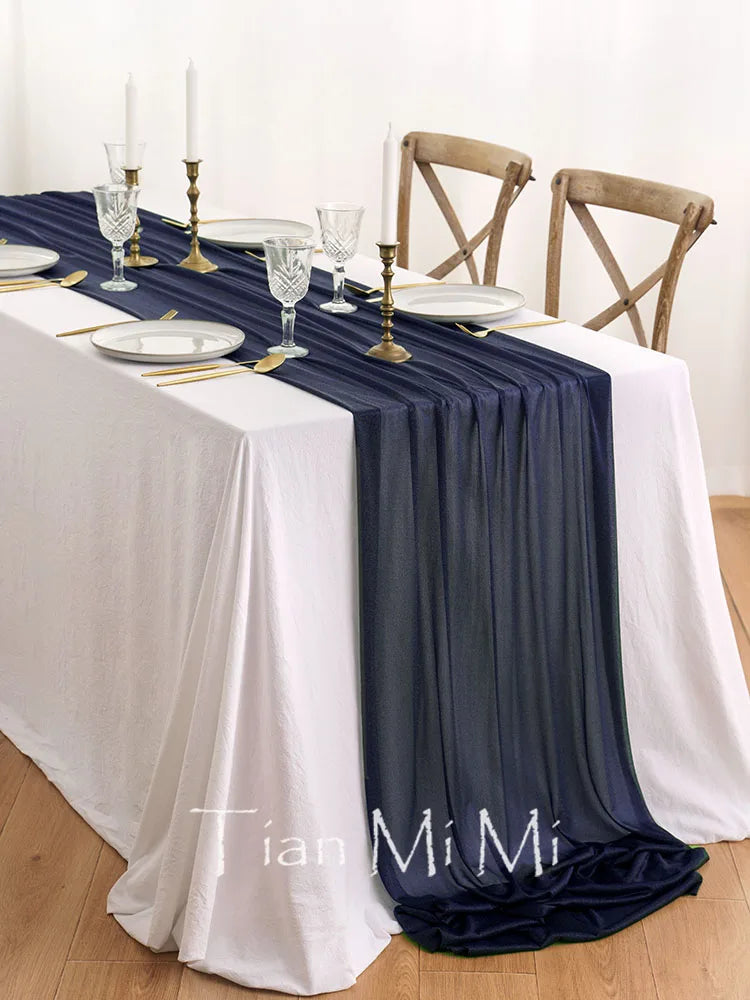 Élégante table dressée avec des chandelles, des verres cristallins et un chemin de table bleu foncé, offrant une atmosphère chic et raffinée.