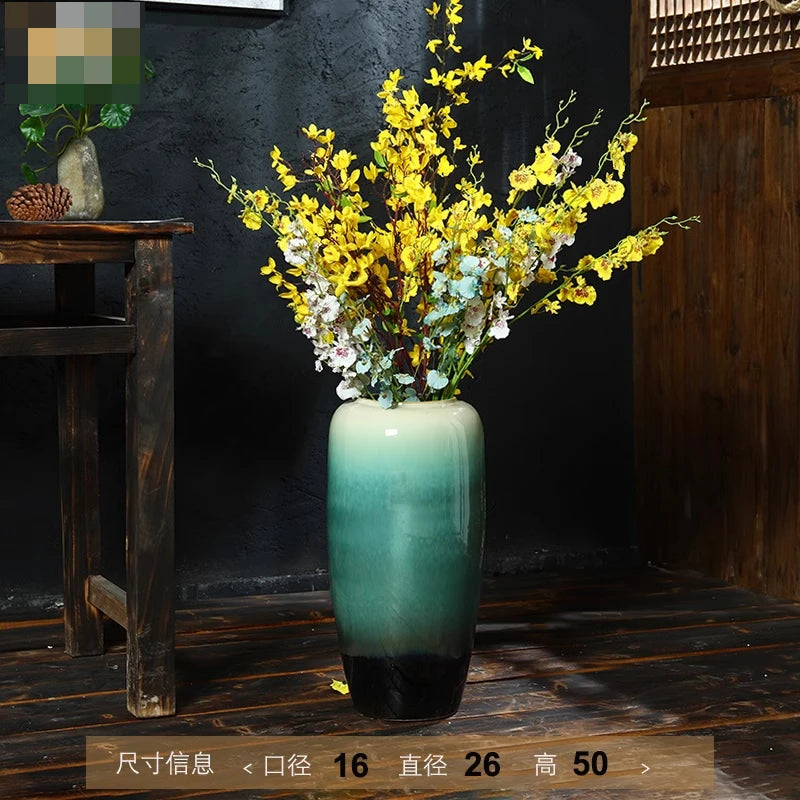 Un grand bouquet de fleurs jaunes et blanches dans un vase vert posé sur un meuble en bois ancien.