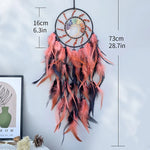 Un capteur de rêves coloré avec des plumes roses et noires, créant une décoration murale unique et bohème.