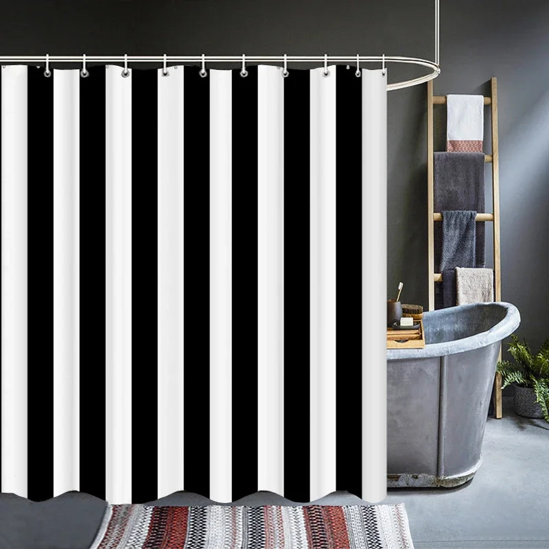 Rideau de douche à rayures noires et blanches suspendu sur une tringle arrondie, installé devant une baignoire en métal style industriel. Salle de bain élégante avec échelle porte-serviettes et tapis décoratif